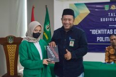 Pemberian buku oleh Kepala Biro Administrasi Kemahasiswaan Unas Kamaruddin Salim, S.Sos.,M.Si. (kanan) kepada mahasiswi (kiri) dengan pertanyaan terbaik