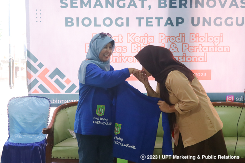 Penyerahan baju kepada siswi SMAN 69 Jakarta (kiri) oleh Ketua Program Studi S1 Biologi Dra. Noverita, M.Si. (kanan)