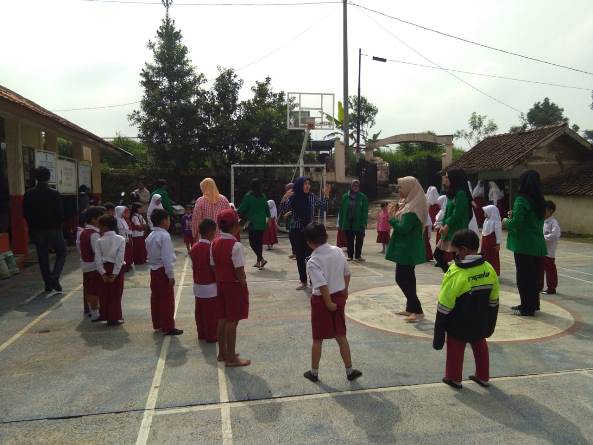 Dosen dan mahasiswa sedang bermain dengan anak-anak sekolah dasar