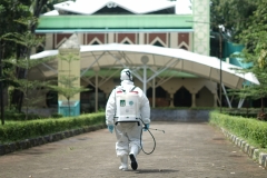 Petugas berjalan menuju masjid STA UNAS untuk menyemprotkan disinfektan agar terbebas dari covid-19 pada Minggu (22/3)