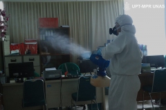 Petugas menyemprotkan disinfektan di sekretariat sekolah pascasarjana UNAS pada Rabu (25/3)