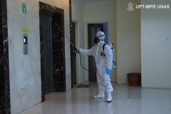 Petugas menyemprotkan disinfektan di sekitar lift sekolah pascasarjana UNAS pada Rabu (25/3)