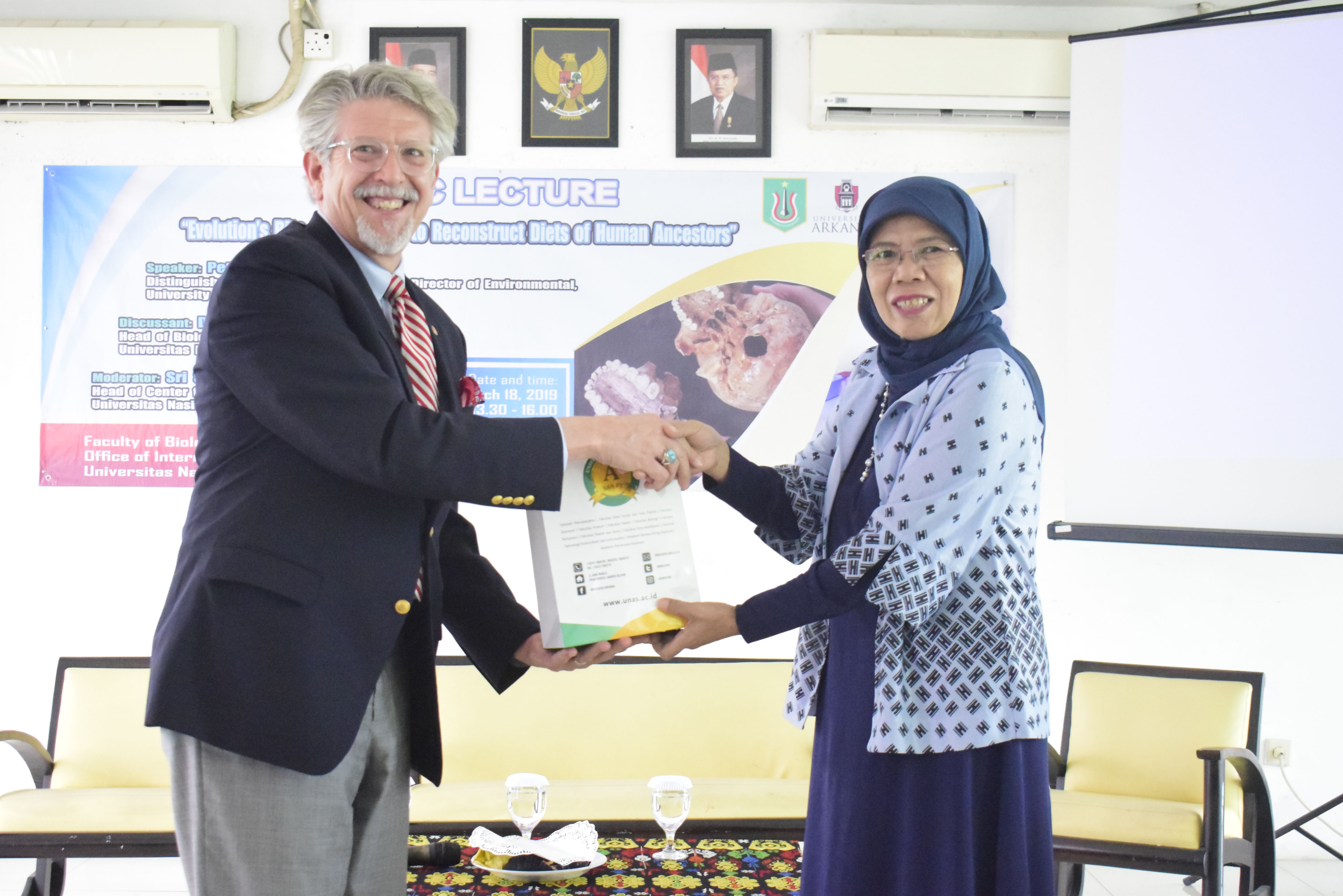 pemberian cenderamata kepada Dean for International Education Graduate School and International Education, Curt Rom, Ph.D. dari panitia, Dra. Dwi Andayaningsih, MM, MSi, di Jakarta (18/3).