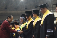 Drs. Drs. Anak Agung Gede Ngurah Puspayoga (Menteri Koperasi dan Usaha Kecil dan Menengah Indonesia) memberikan selamat kepada wisudawan terbaik