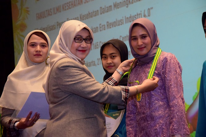 Penyematan penghargaan kepada mahasiswa terbaik oleh Dekan Fakultas Ilmu Kesehatan  Dr. Retno Widowati, M.Si (kiri)